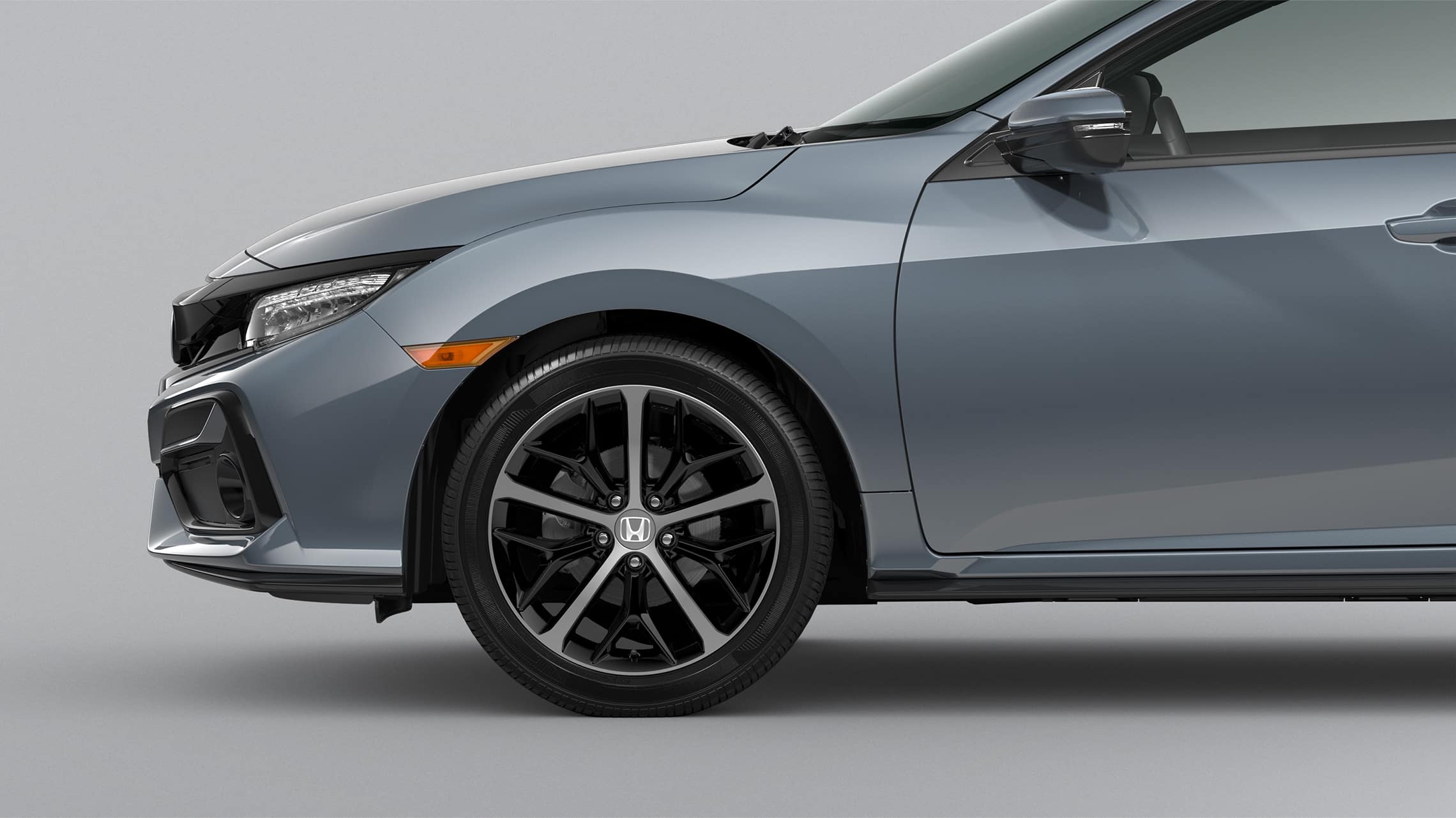 Detalle frontal de ruedas de aleación de 18 pulgadas del lado del pasajero en el Honda Civic Sport Touring Hatchback 2021 en Sonic Gray Pearl.