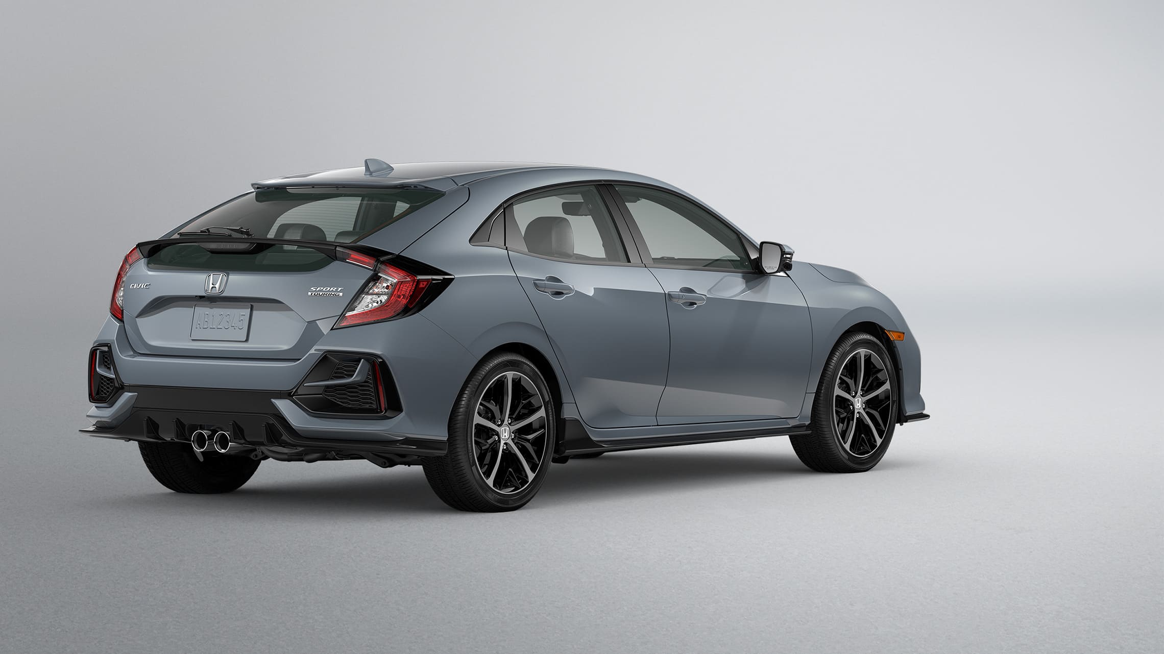 Rear 3/4 driver-side view of 2020 Honda Civic Sport Touring Hatchback in Sonic Gray Pearl.
